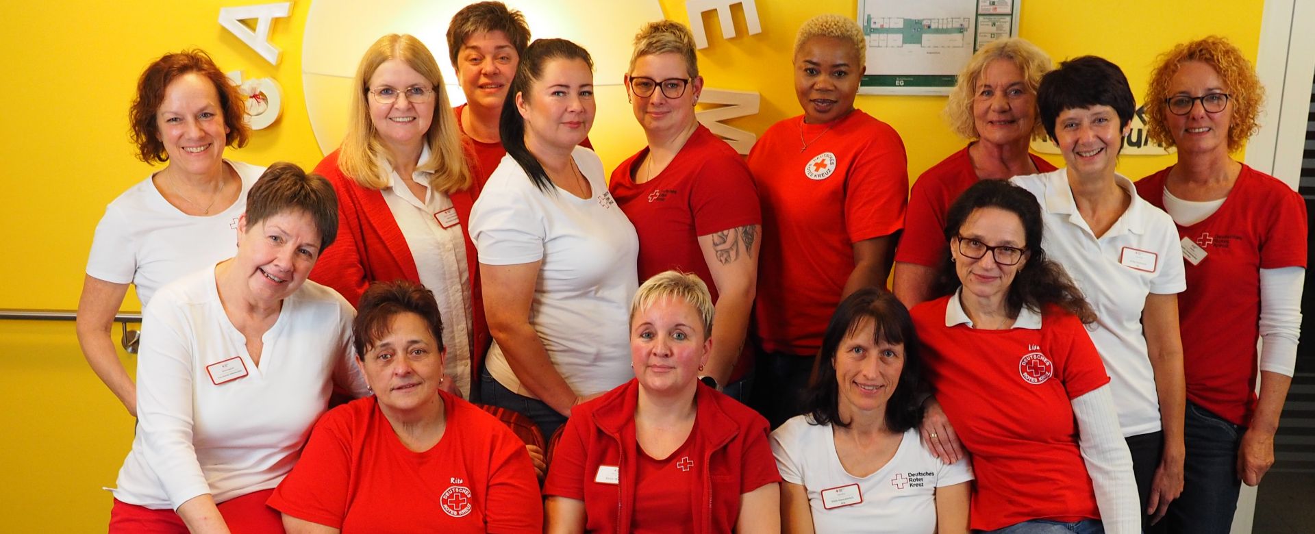 Foto: Eine Mitarbeiterin des Rotkreuz-Shops zeigt einer jungen Frau ein Kleidungsstück mit Kleiderbügel. Die junge Frau freut sich.