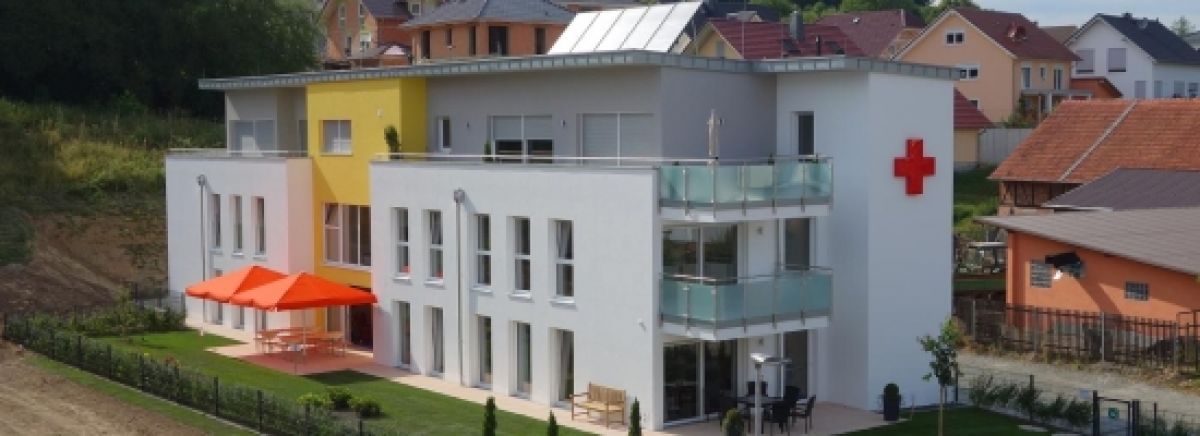 Foto: In einem DRK-Kleiderladen stehen zwei Kunden mit ihren neuen Kleidungsstücken an der Kasse. Sie freuen sich über ihren Fund.