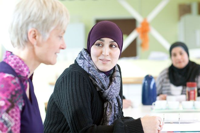 Foto: Eine junge Frau mit farbigem Kopftuch befindet sich in einem Beratungsgespräch. Sie blickt gelöst und zufrieden in Richtung der Beraterin.